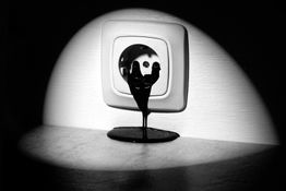 Schwarze Flüssigkeit fließt aus einer Steckdose, dramatisch beleuchtet.