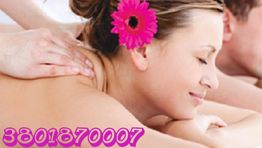 Donna rilassata riceve un massaggio con fiore tra i capelli. Numero di telefono in basso a sinistra.