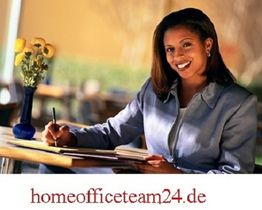 Frau in blauem Anzug schreibt lächelnd an einem Tisch; Vase mit gelben Blumen.