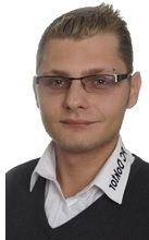 Eine Person in Hemd und Brille lächelt in die Kamera.