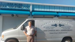 Man standing beside a lock shop van in front of a building under a clear blue sky.