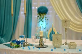 Elegante Tischdekoration in Türkis und Creme mit Kerzen und Blumen.