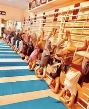 Personas practican yoga en la pared en una clase grupal, colgando boca abajo con cuerdas.