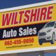 Billboard for Wiltshire Auto Sales with contact info and a car image on a yellow background.