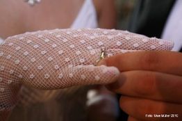 Hand mit weißem Netz-Handschuh hält einen Ring.