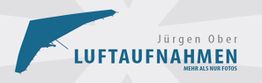 Logo mit blauem Drachenflieger, Text: "Jürgen Ober Luftaufnahmen - Mehr als nur Fotos".