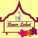 Logo mit einem Buddha, Schriftzug "Baan Sabai" und Blumen auf gelbem Hintergrund.