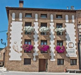 Fachada de edificio con flores en balcones y un cartel que dice "LA CASA DEL REBOTE".