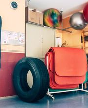 Fitnessraum mit Boxsack, Reifen, roten Matten und Gymnastikbällen an der Wand.