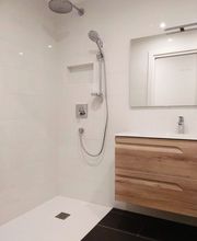 Baño moderno con ducha, espejo y lavabo con cajones de madera.