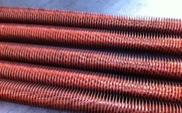 Bobine metalliche rosse con alette, disposte in parallelo su una superficie piatta.