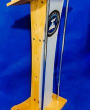 Atril de madera y metal con sello oficial, fondo azul.