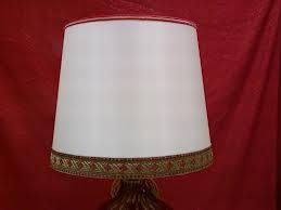 Paralume bianco con bordo decorativo su sfondo rosso.