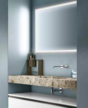 Bagno moderno con specchio illuminato, lavabo in pietra e pareti azzurre.