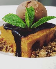 Bizcocho con chocolate, bola de helado y hojas de menta en plato blanco.