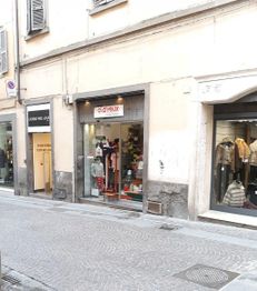 Facciata di un negozio su una strada cittadina con vetrine di abbigliamento.