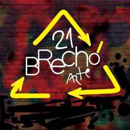 Arte urbana em parede de tijolos com triângulo amarelo e texto "21 Brechó Arte" em branco.
