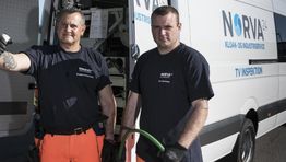 To mænd foran en Norva24-køretøj iført arbejdstøj og holder udstyr.