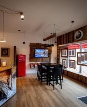 Gemütliches Café mit Holzmöbeln, rotem Kühlschrank und großen Fenstern zur Straße.