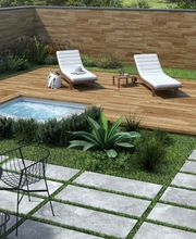 Giardino moderno con piscina, lettini bianchi, tavolo nero e sedie su prato verde e pietre.