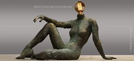 Bronzeskulptur med en glødepære som hoved, sidder afslappet mod en grå baggrund.