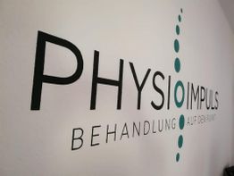 Aufschrift "PHYSIO IMPULS, Behandlung auf den Punkt" an einer Wand mit grafischem Punktmuster.