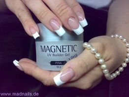 Hände mit French Nails halten ein UV Builder Gel. Eine Perlenkette ist um das Handgelenk.