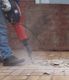 Worker using a jackhammer to break up old tiles.