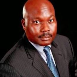 Man in a suit with a blue tie on a black background.