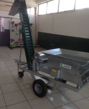 Macchinario metallico su ruote in un'officina, con un nastro trasportatore inclinato.