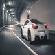 A white sports car speeds through a well-lit tunnel at night.