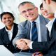 Business people smiling and shaking hands at a meeting.