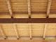 Vista di un soffitto in legno con travi esposte, inquadrato dal basso.