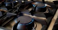 Close-up view of a gas stove with blue flames on multiple burners.