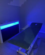 Camilla de masaje en habitación iluminada con luz azul tenue.