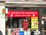 FC Bayern Fan-Shop mit roten Trikots und Lotto-Schildern im Schaufenster.