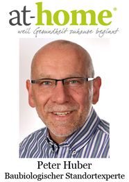 Mann mit Brille und Hemd lächelt. Text: "at-home" und "Peter Huber, Baubiologischer Standortexperte".