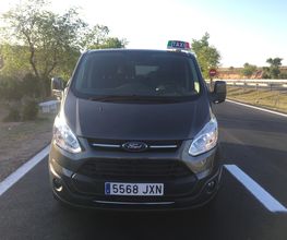 Taxi negro con matrícula 5568 JXN estacionado en una carretera rural bajo un cielo despejado.
