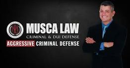 Smiling man in a suit next to Musca Law logo and text "Aggressive Criminal Defense."