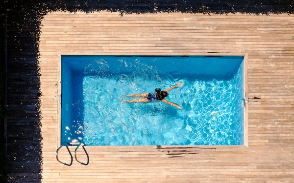 Frau schwimmt im Pool bei sonnigem Wetter
