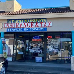 Storefront with signs for insurance, tax, and translation services in Spanish and English.