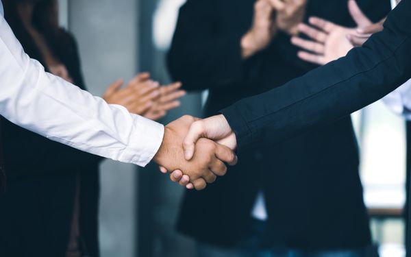 Zwei Geschäftsleute schütteln sich die Hände zum erfolgreichen Unternehmensverkauf.