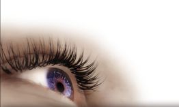 Nahaufnahme eines Auges mit langen Wimpern, das zur Seite blickt.