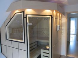 Moderne Heimsauna mit Holzverkleidung und Beleuchtung in einem Zimmer mit Fliesenboden.
