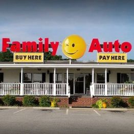 Family Auto storefront with a winking smiley face and signs: "Buy Here, Pay Here."