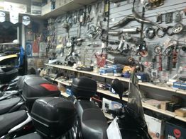 Negozio di ricambi per moto, con accessori appesi alle pareti e motociclette in primo piano.