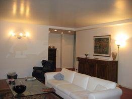 Soggiorno moderno con divano bianco, lampade, quadro e mobili in legno.