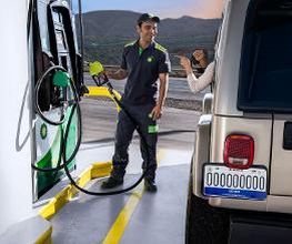 Persona surtiendo gasolina en una estación de servicio junto a un vehículo todoterreno.
