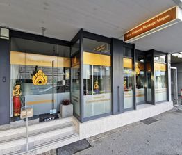 Thai-Massage-Salon mit Glasfront, gelben Schildern und Statue am Eingang.
