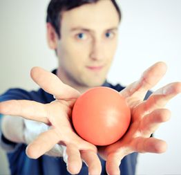 Person hält einen roten Ball mit ausgestreckter Handfläche in die Kamera.